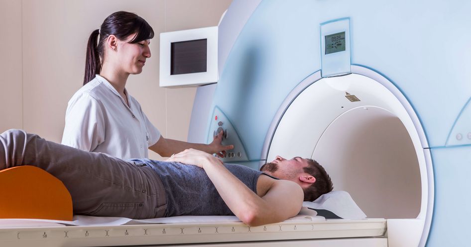 Eine Krankenpflegerin schiebt einen Patienten ins MRT