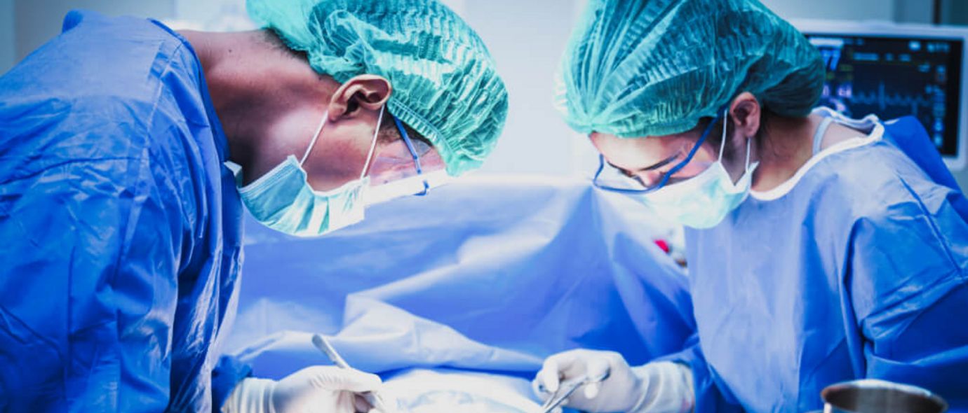Eine Ärztin und ein Arzt mit Mundschutz sortieren chirurgische Instrumente vor einer Operation