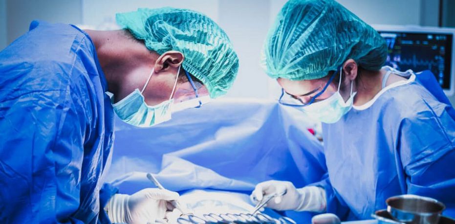 Eine Ärztin und ein Arzt mit Mundschutz sortieren chirurgische Instrumente vor einer Operation