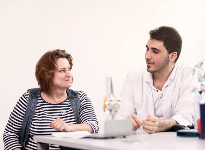 Orthopäde spricht mit Patientin über Kniegelenksmodell