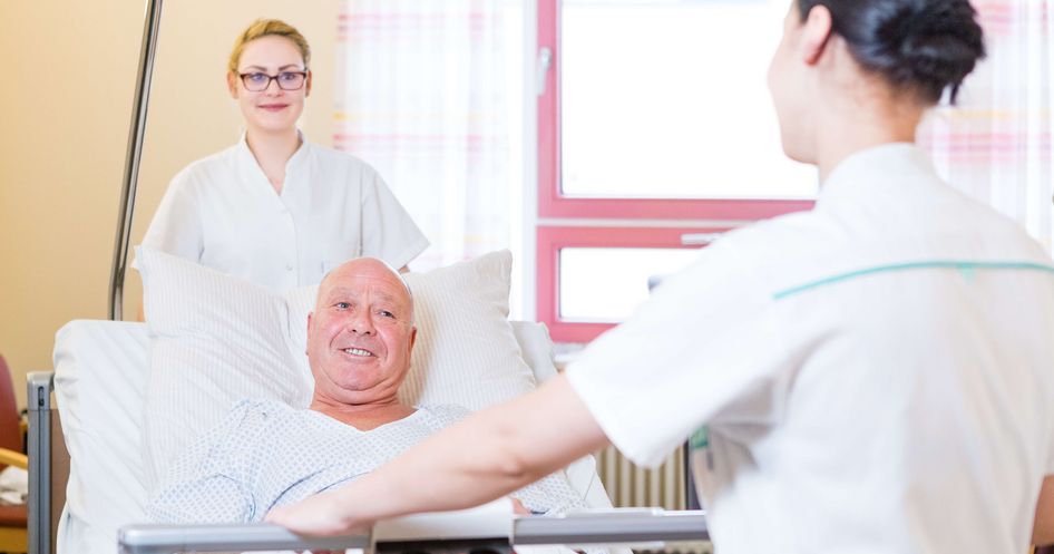 Zwei Krankenpfleger schieben ein Bett mit einem Patienten