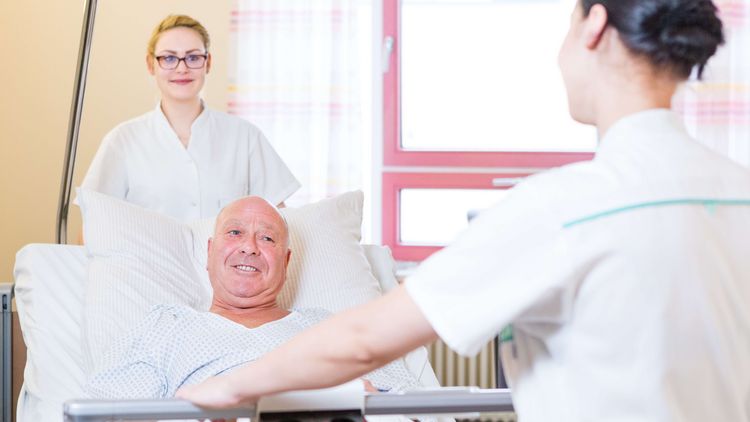 Zwei Krankenpfleger schieben ein Bett mit einem Patienten